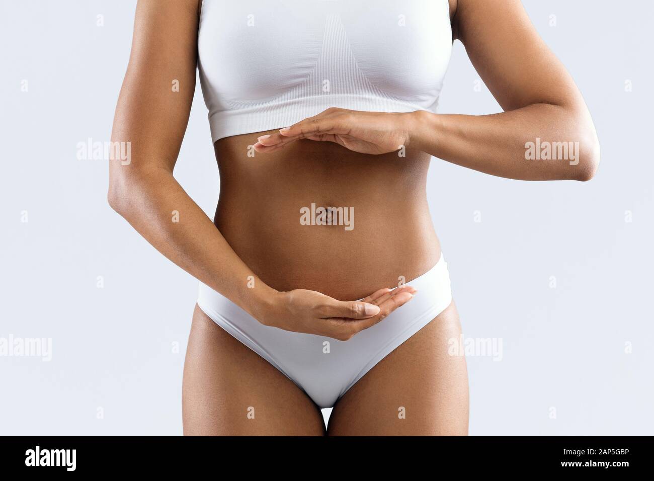 Afro woman holding her hands next to flat tummy Stock Photo