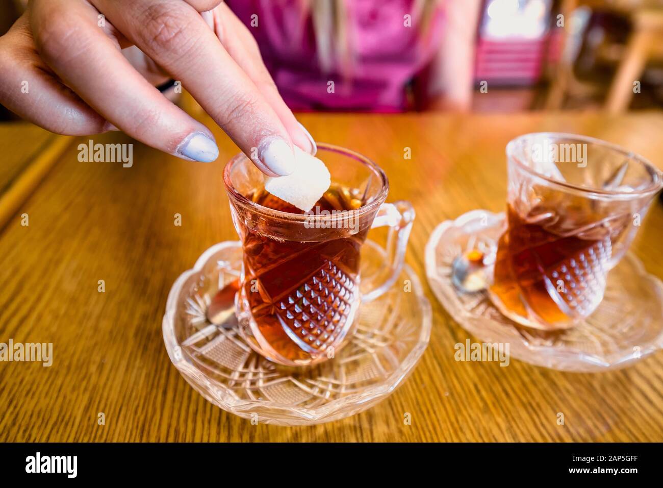 Woman's hand putting shugar to one of two tot glasses of tea at Petra,  Jordan Stock Photo - Alamy