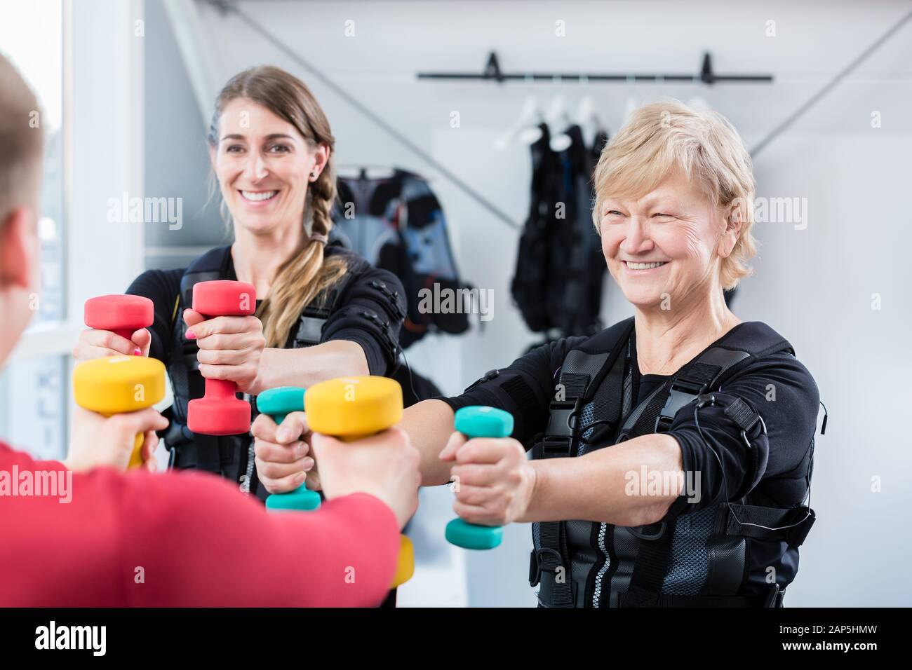 Senior and young woman with dumbbells in wireless ems gym Stock Photo ...