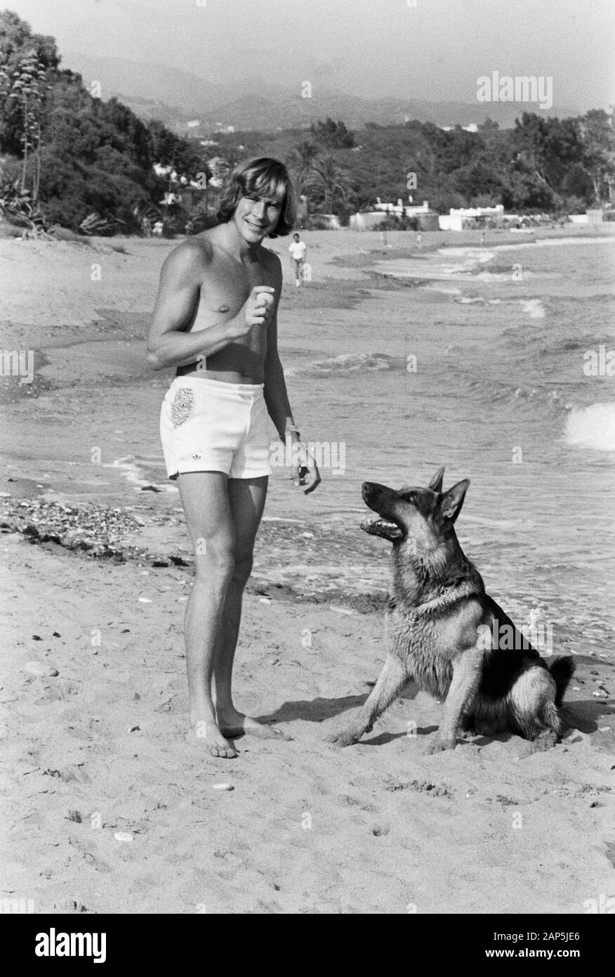 James Hunt, britischer Autorennfahrer, mit seinem Hund am Strand, um 1974. British car racing driver James Hunt with his pet dog on the beach, around 1974. Stock Photo