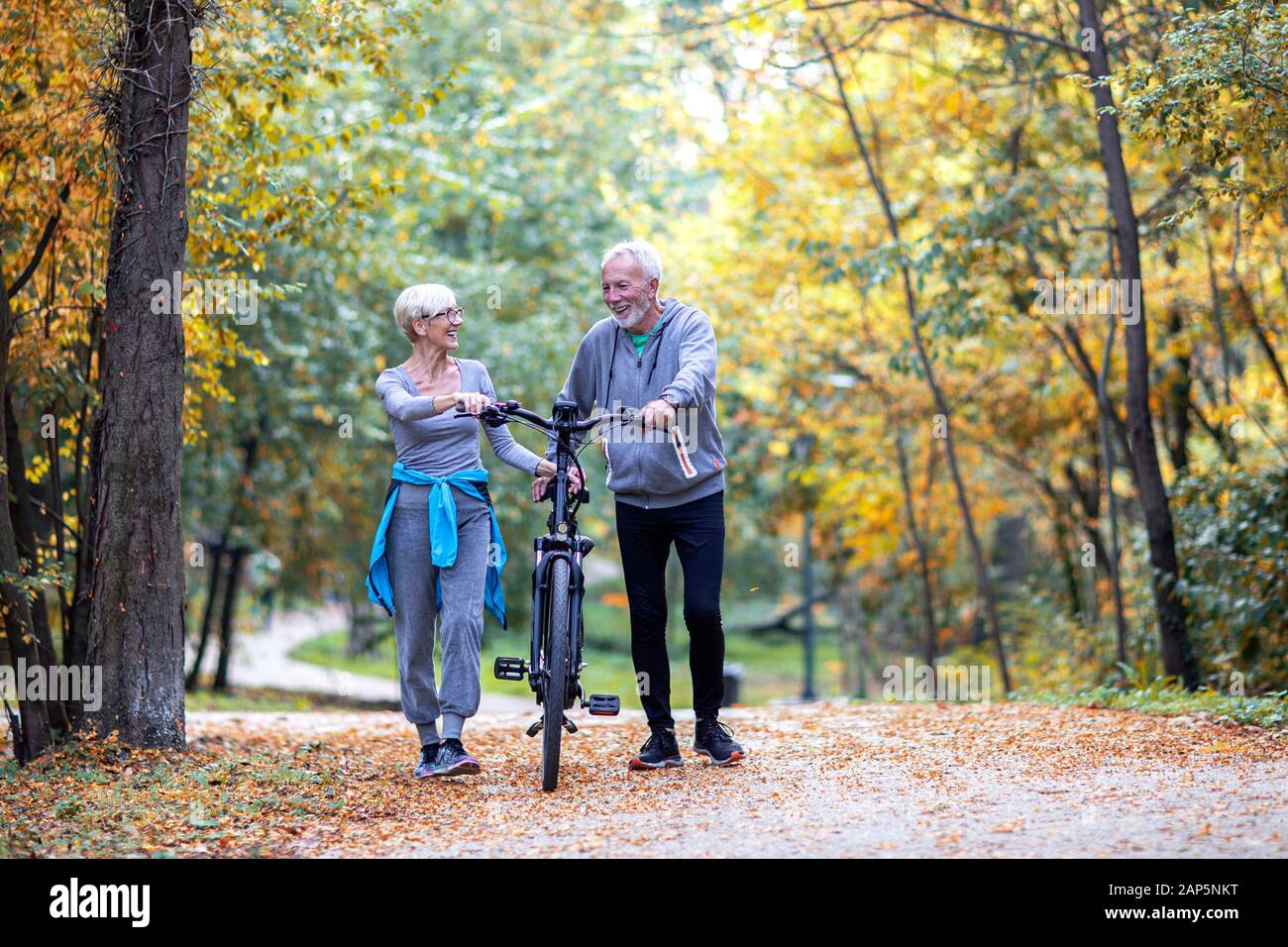 Old couple with bike on public park walk and talk Stock Photo