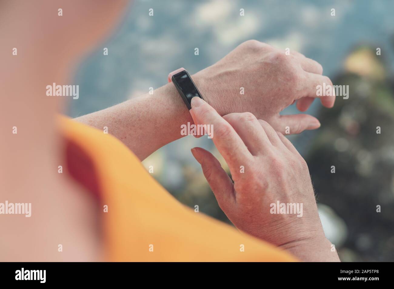 Woman hiker using smart bracelet during trekking in nature. Close up of female hands with portable information device, selective focus. Stock Photo