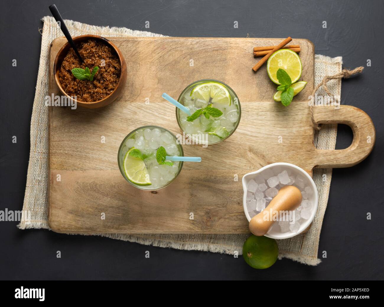 Caipirinha, lime, fresh mint, brown sugar and crushed ice. Rustic environment with black background. Aerial View Stock Photo
