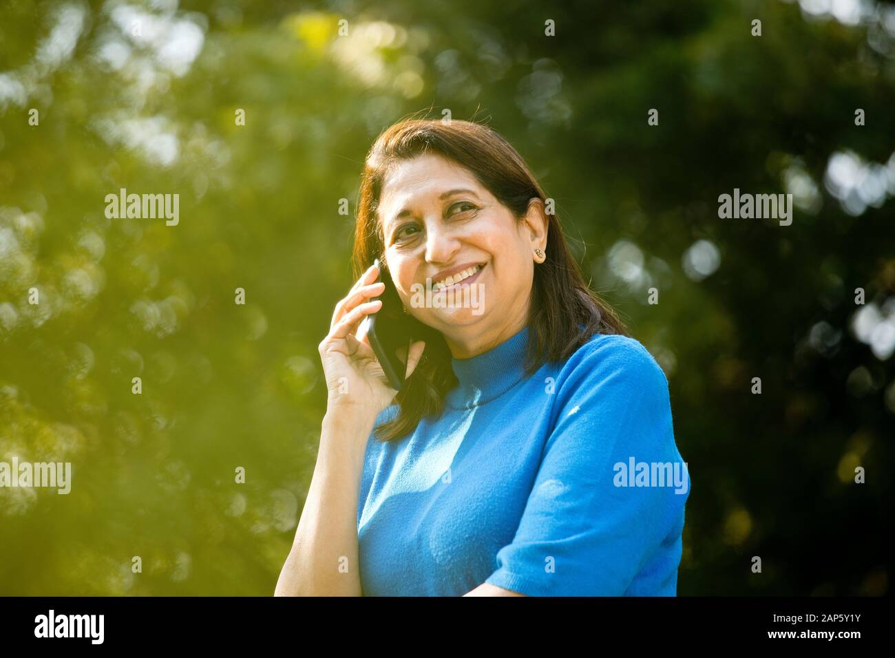 Happy senior woman using phone at park Stock Photo