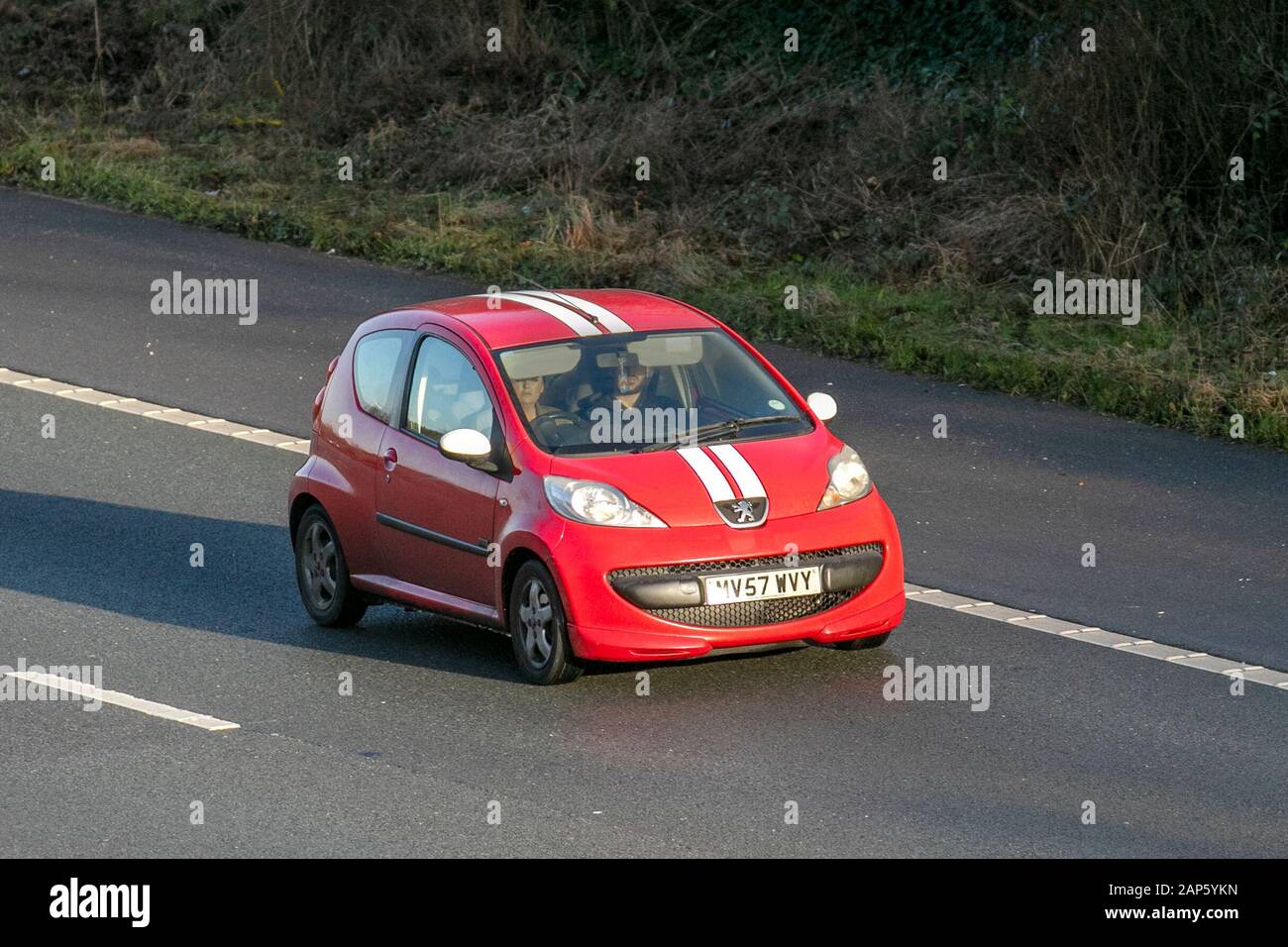 A red Peugeot 107 driving on a motorway, symbolizing the speed and precision needed in real estate investing.
