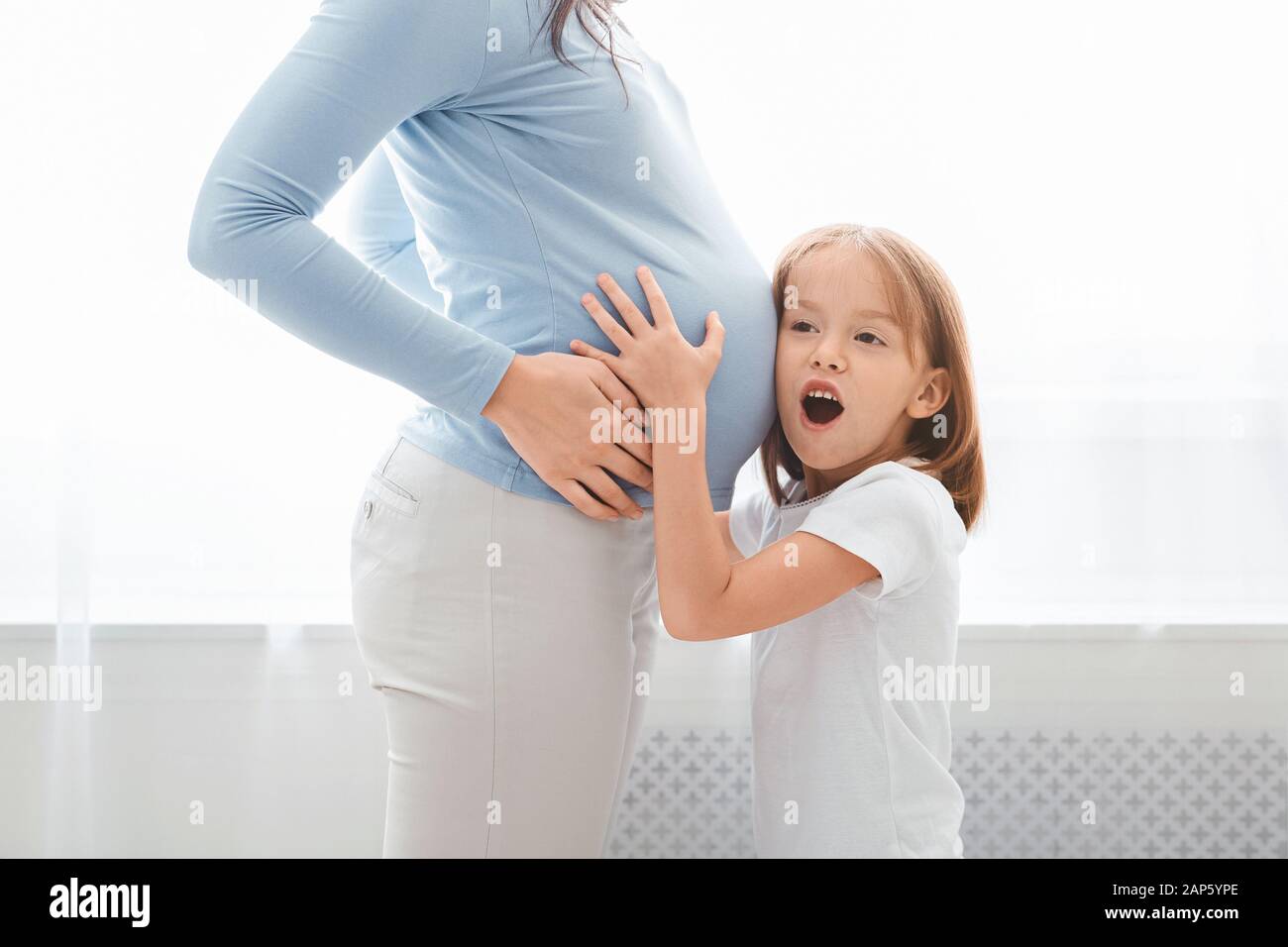 Emotional preschool kid listening to pregnant mom belly Stock Photo - Alamy