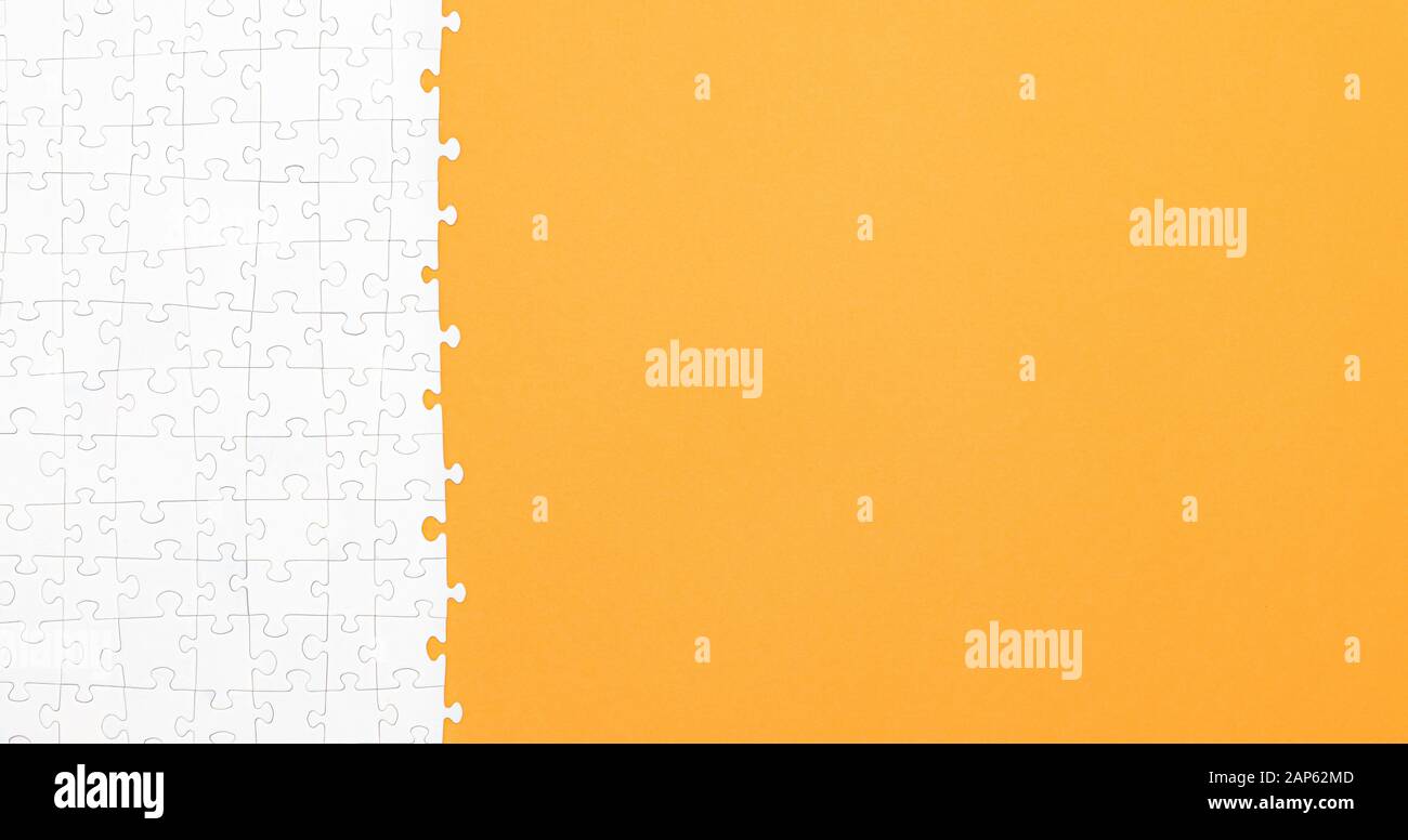 White jigsaw puzzle pieces on orange background copy space for your text. Business concept. Stock Photo