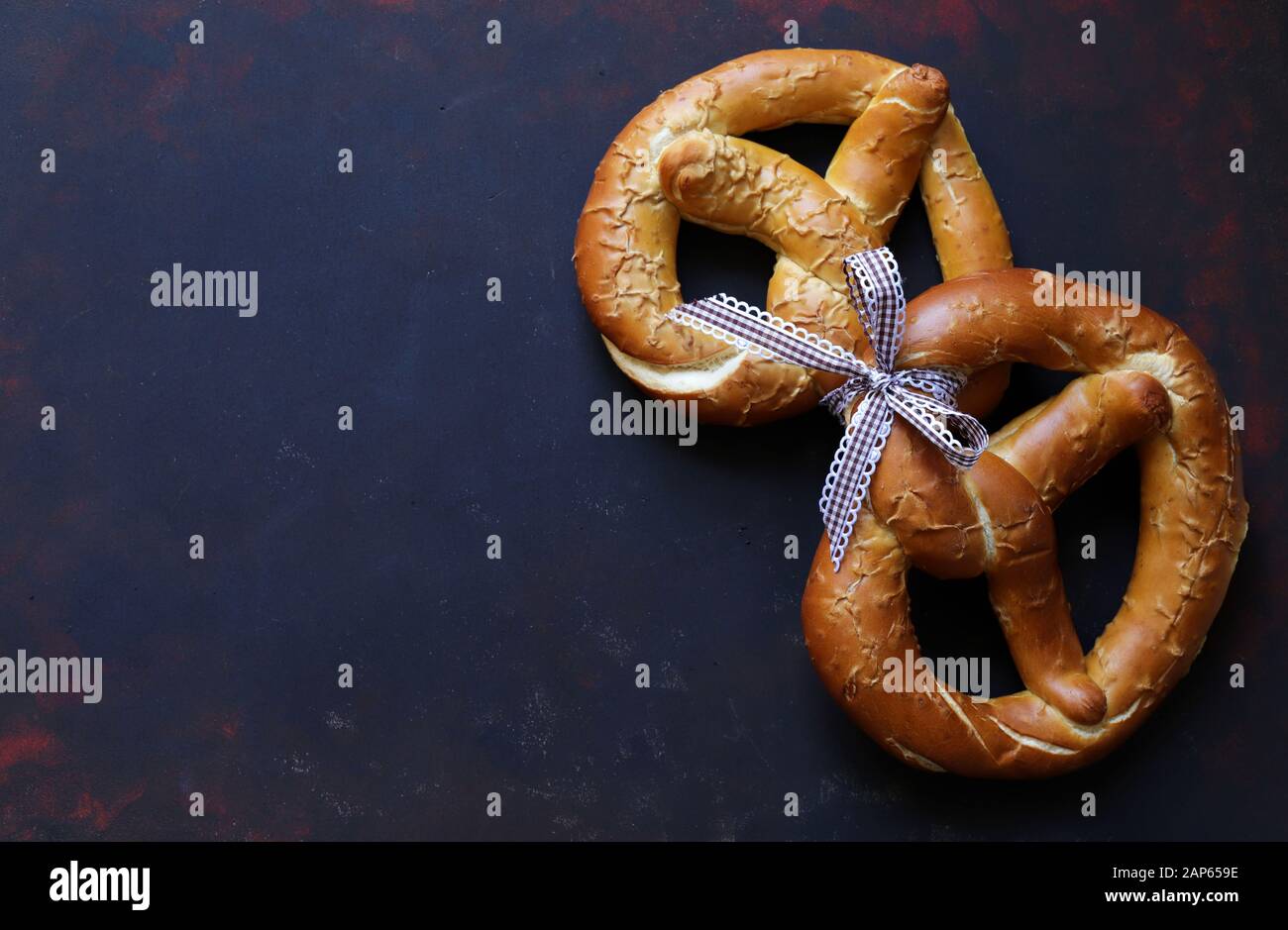 Concept of bavarian food. Traditional baked bavarian salted pretzels on dark background. Stock Photo