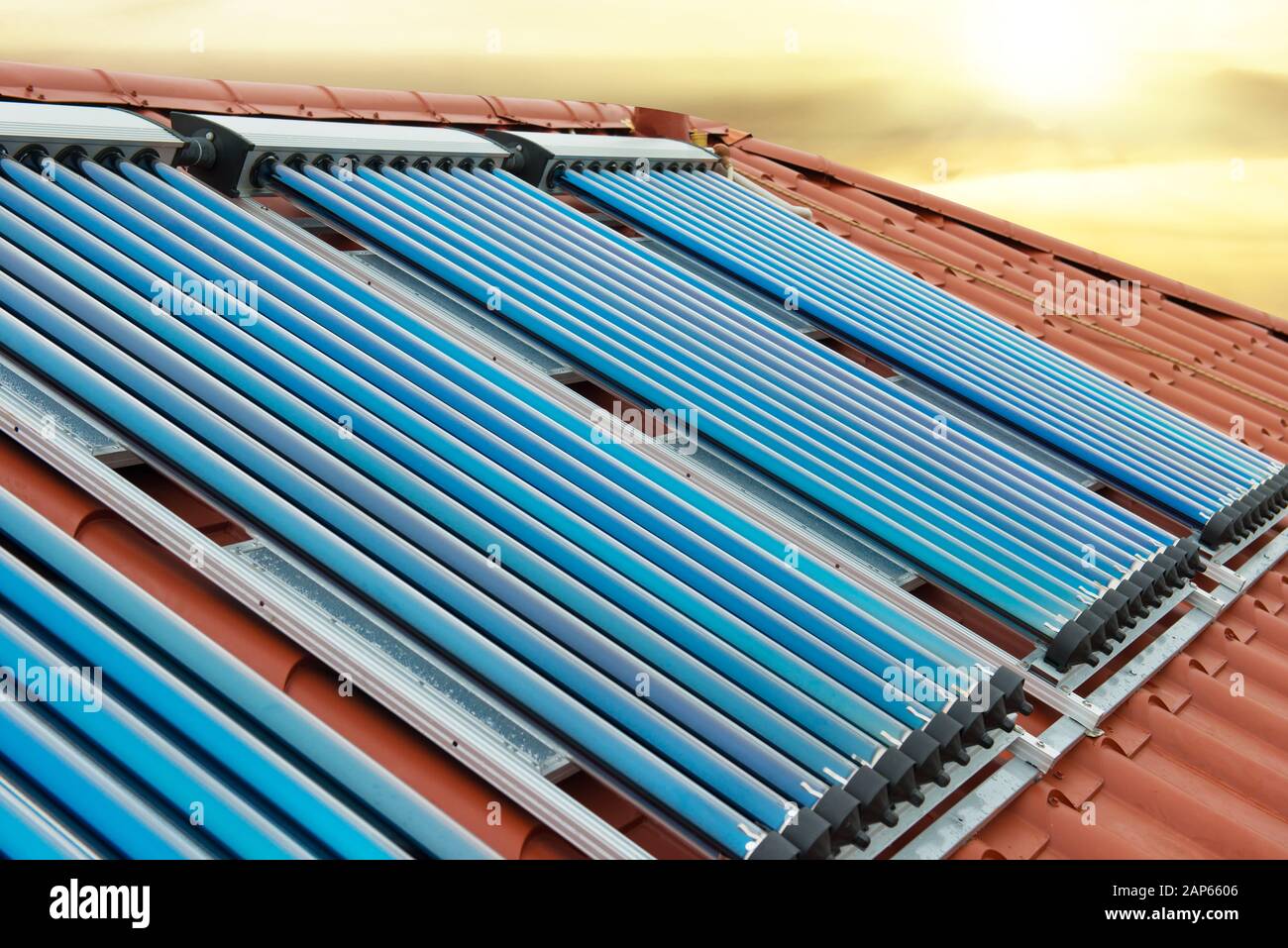 Vacuum collectors- solar water heating system on red roof of the house ...