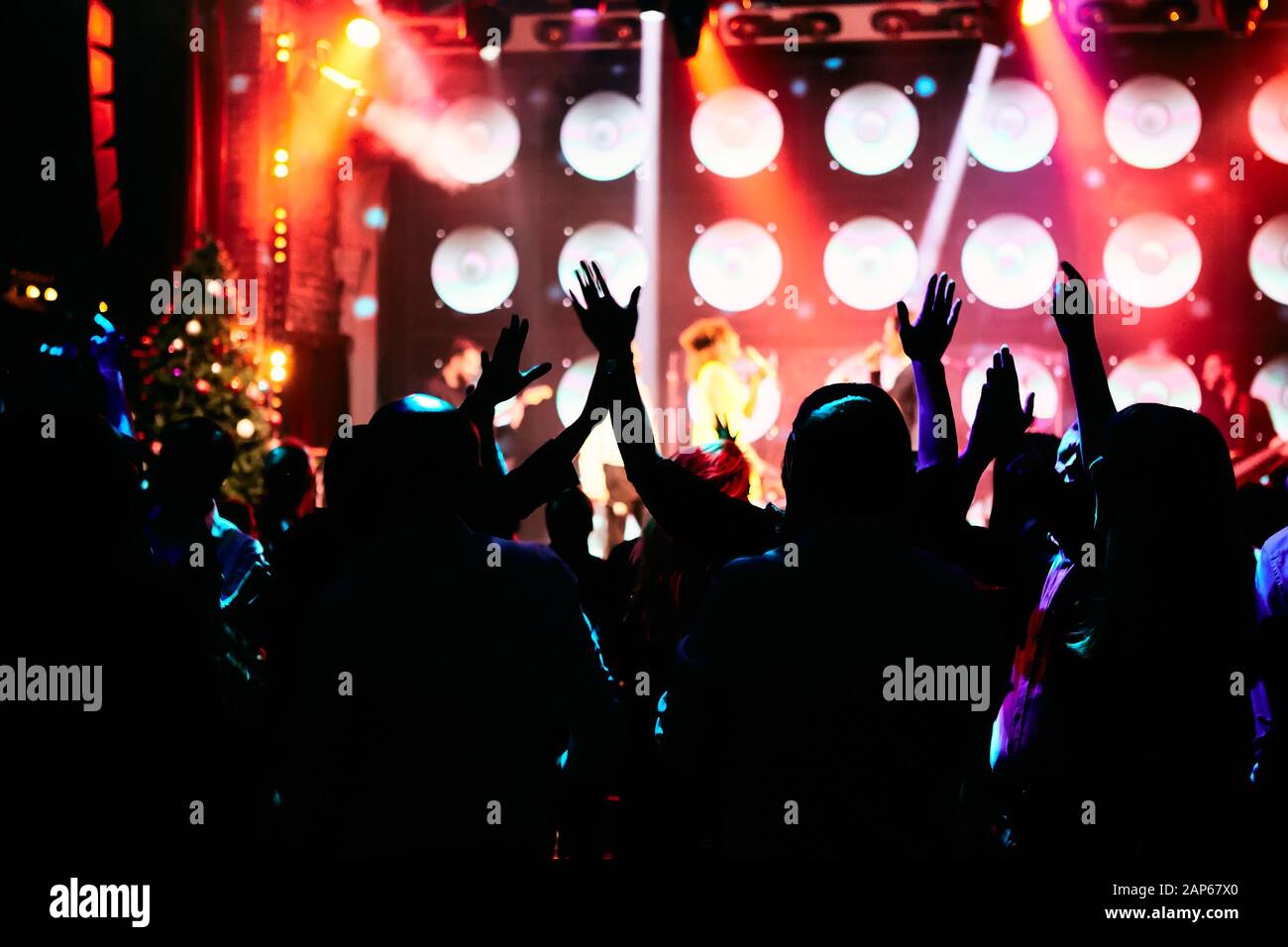 Crowd at a music concert, audience raising hands up in front of bright ...