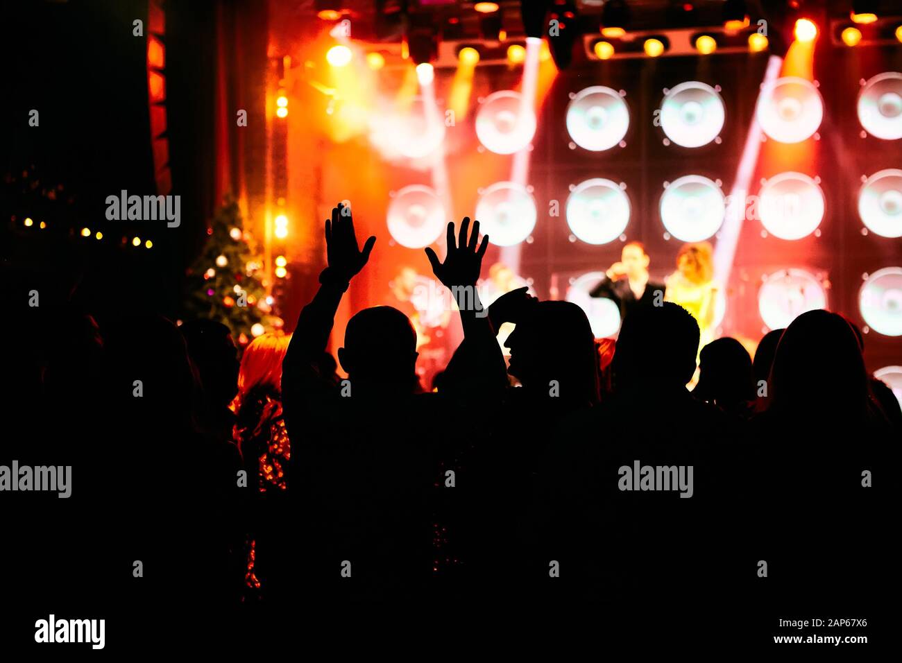 Crowd at a music concert, audience raising hands up in front of bright ...