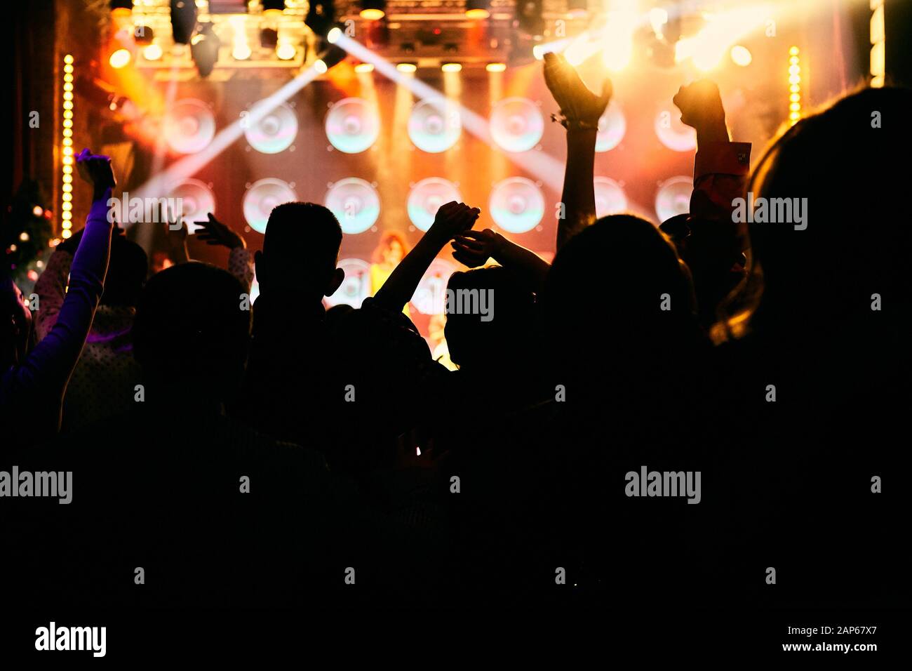 Crowd at a music concert, audience raising hands up in front of bright ...