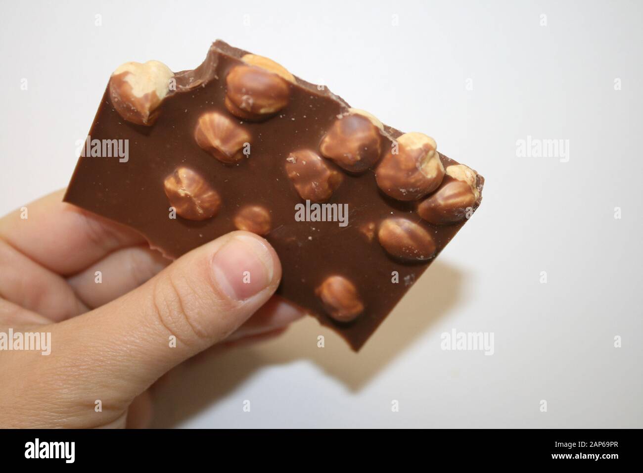 Chocolate with whole hazelnuts in hand Stock Photo