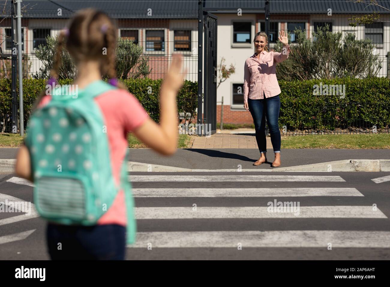 Schoolgirl waving to her mother at a pedestrian crossing Stock Photo ...