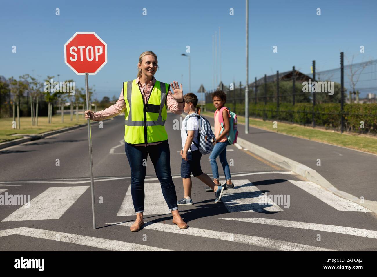 Woman wearing a high visibility vest and holding a stop sign Stock Photo