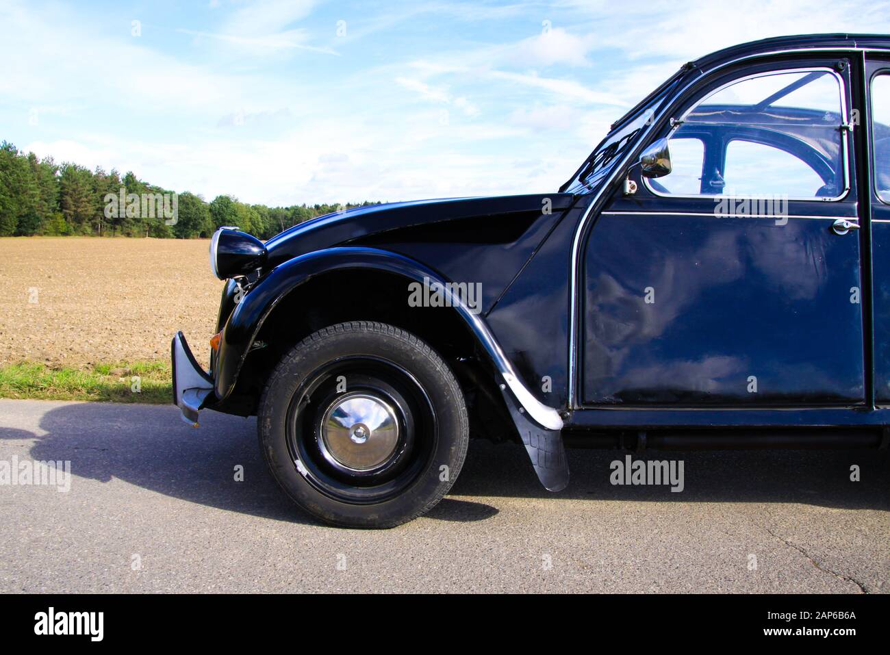 Viersen, Germany - October 12. 2019: Side view on black French classic cult car 2CV with open folding roof against blue sky in rural area Stock Photo