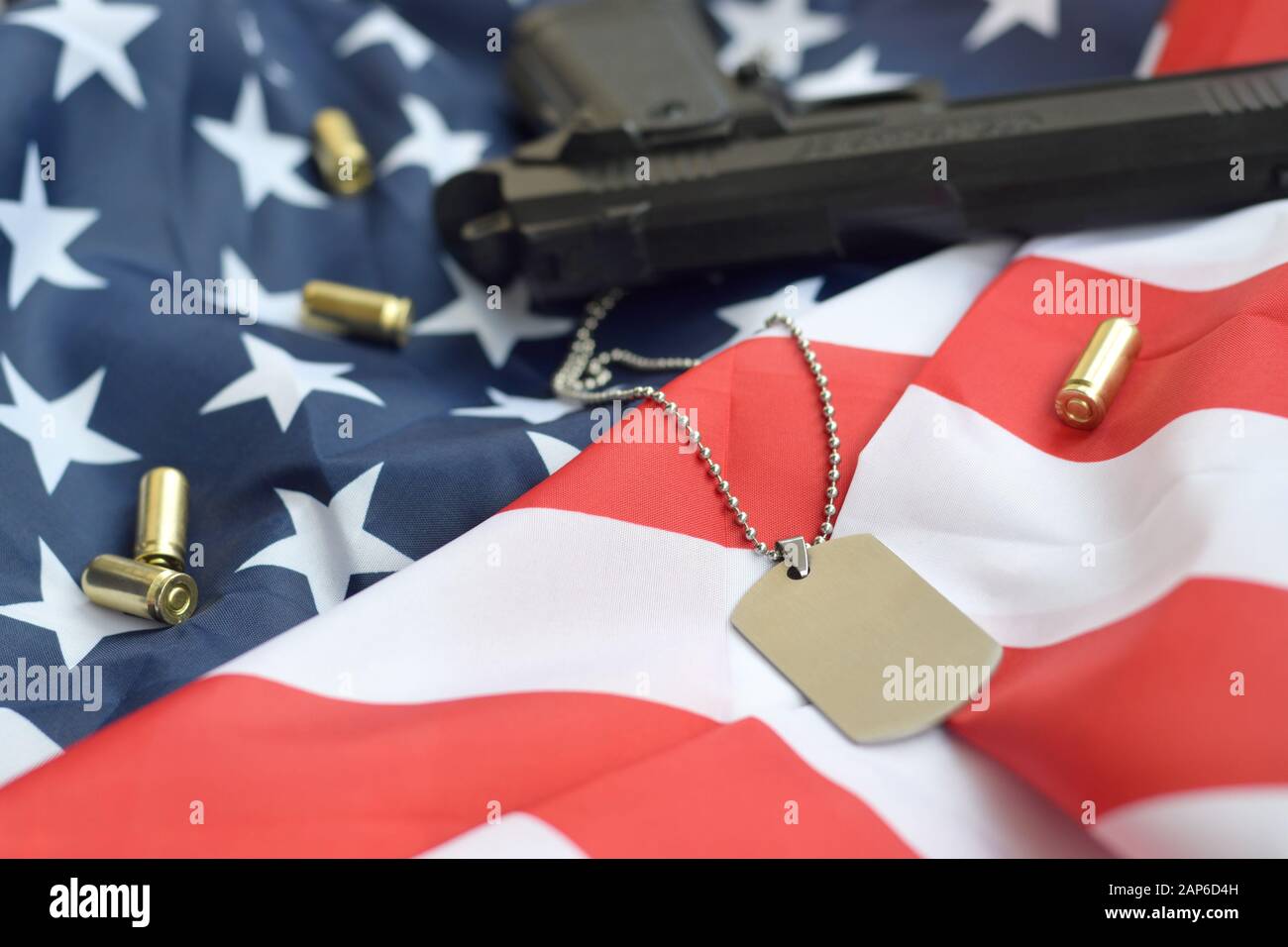 Army Dog tag token with 9mm bullets and pistol lie on folded United ...