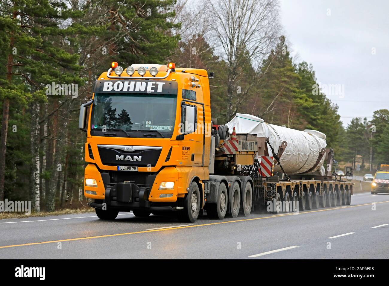 Yellow MAN TGX Bohnet GmbH semi low loader hauls industrial equipment as oversize load accompanied by escort vehicles.Raasepori, Finland. Jan 17, 2020 Stock Photo