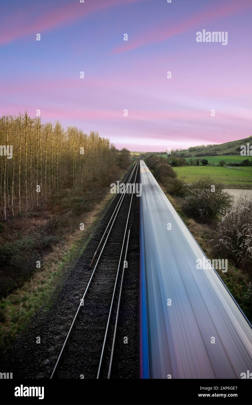 Moving train on a straight track at sunset in the English countryside Stock Photo