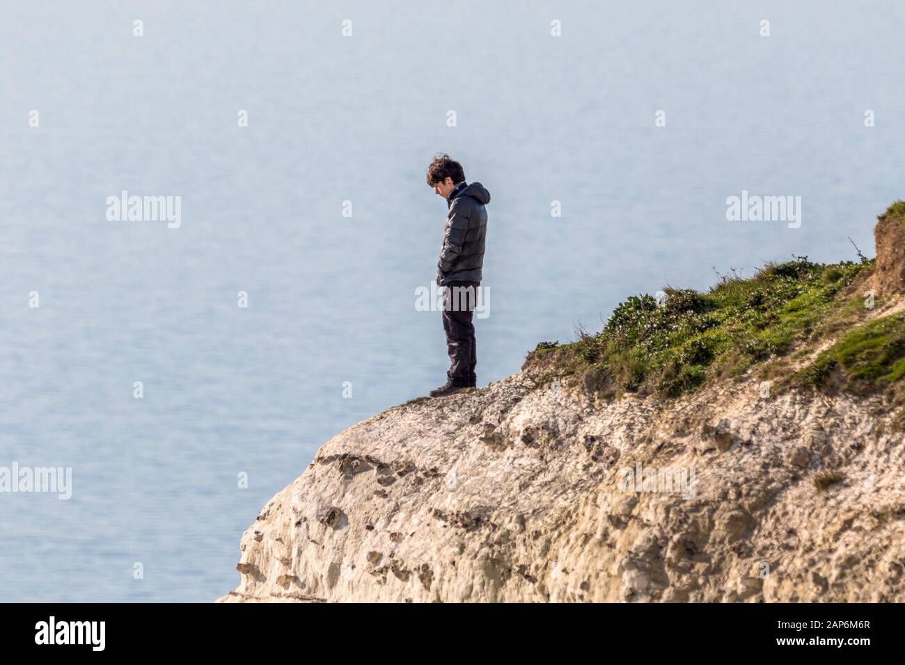 Base jumper prepares to leap off the 400ft cliffs at Beachy Head by standing on the cliff edge. Stock Photo