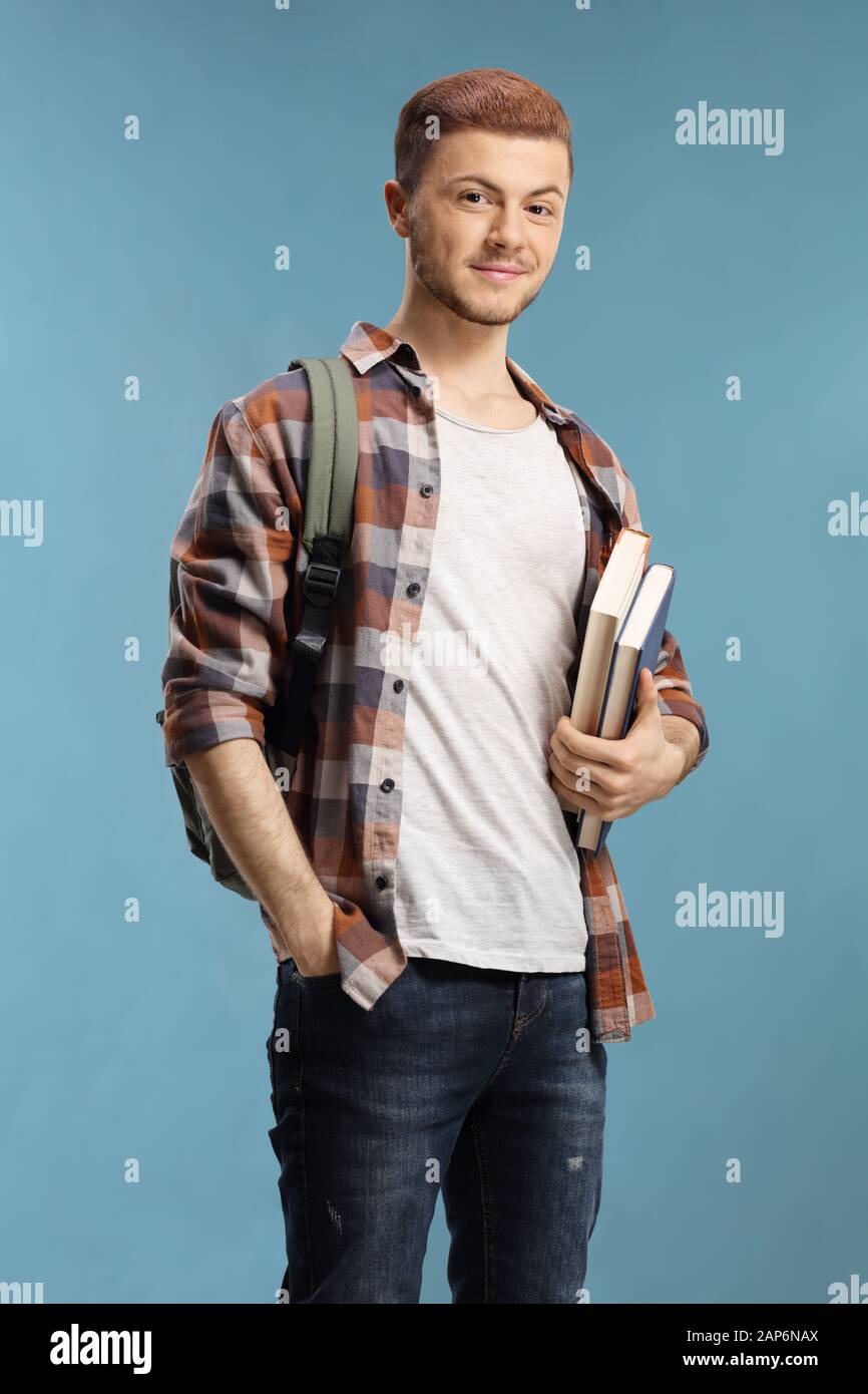 Male student with books and backpack isolated over blue background ...