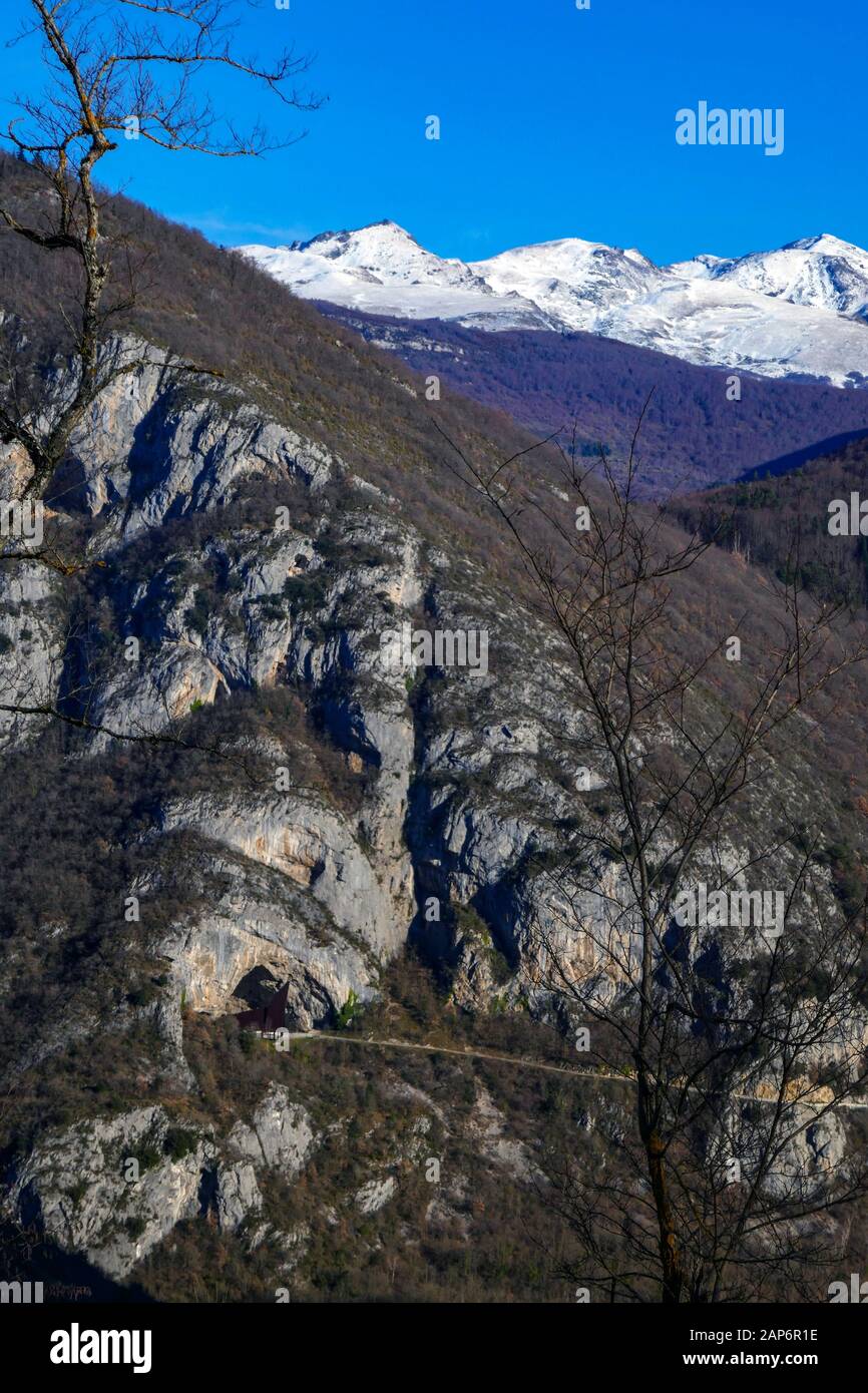 Niaux Cave and access road with snowy Mont Olmes behind, seen from across the valley, Ariege, French Pyrenees, France Stock Photo