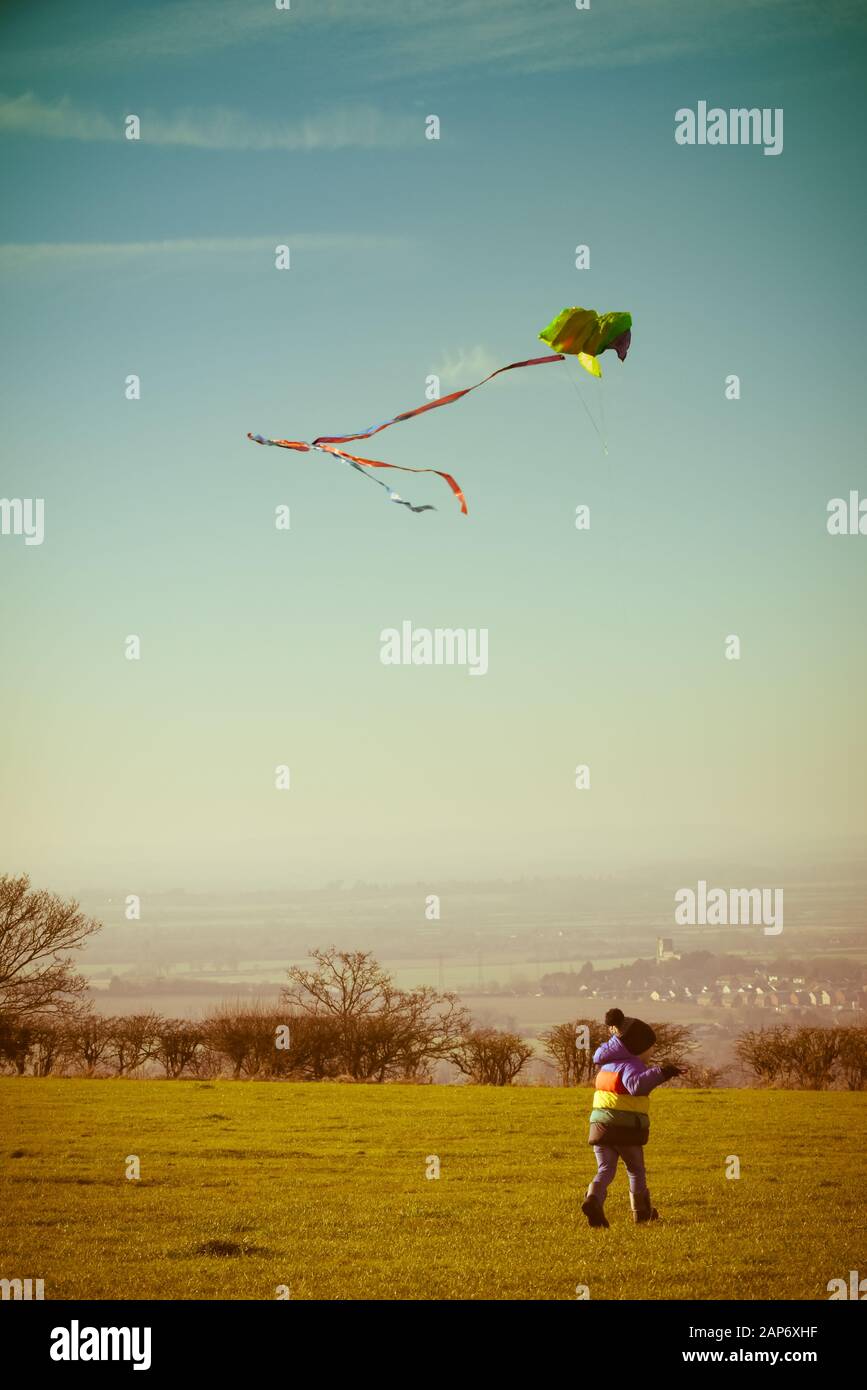 Boy playing outside with a kite, running outdoors during the day with retro style filter Stock Photo