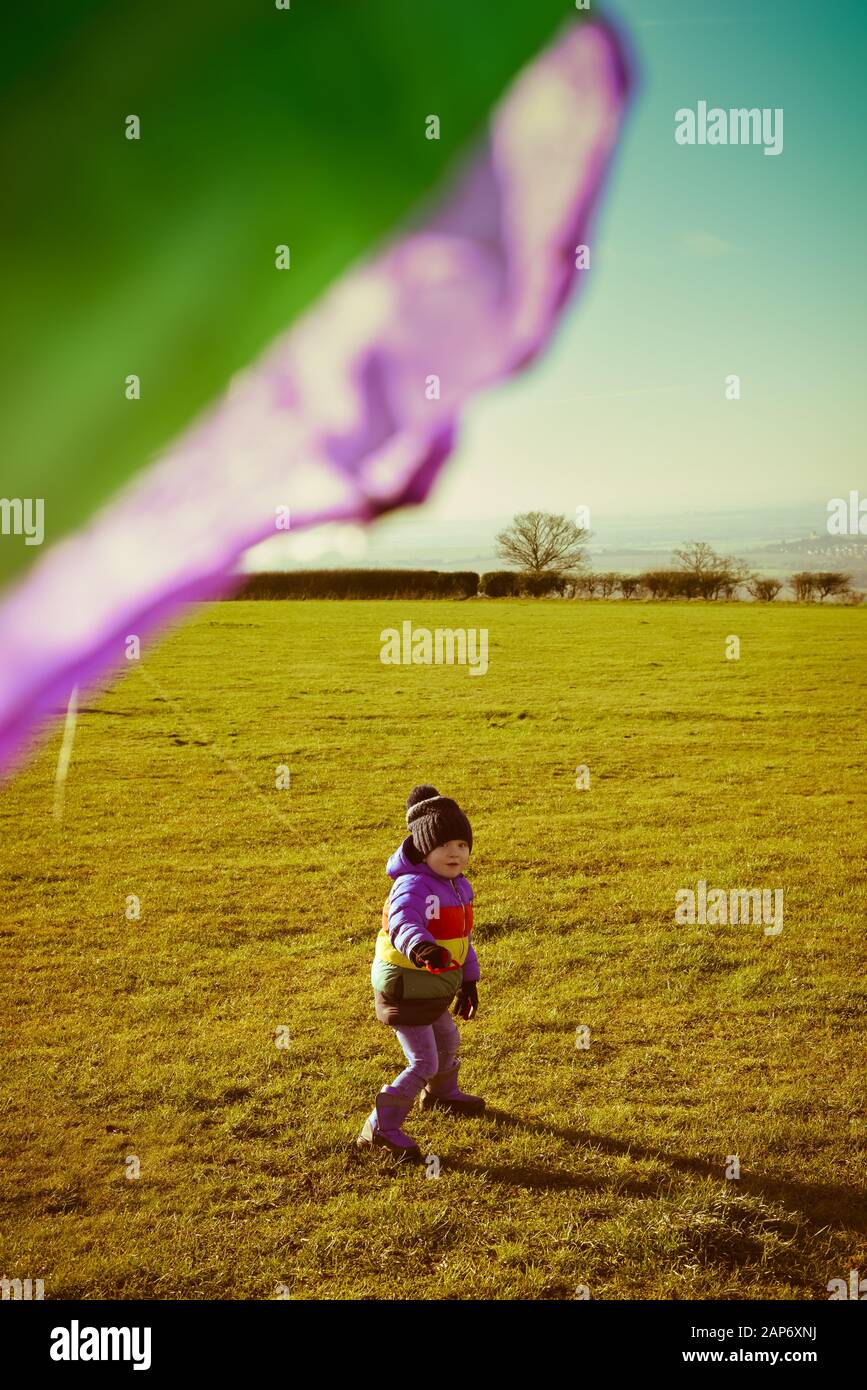 Boy playing outside with a kite, running outdoors during the day with retro style filter Stock Photo