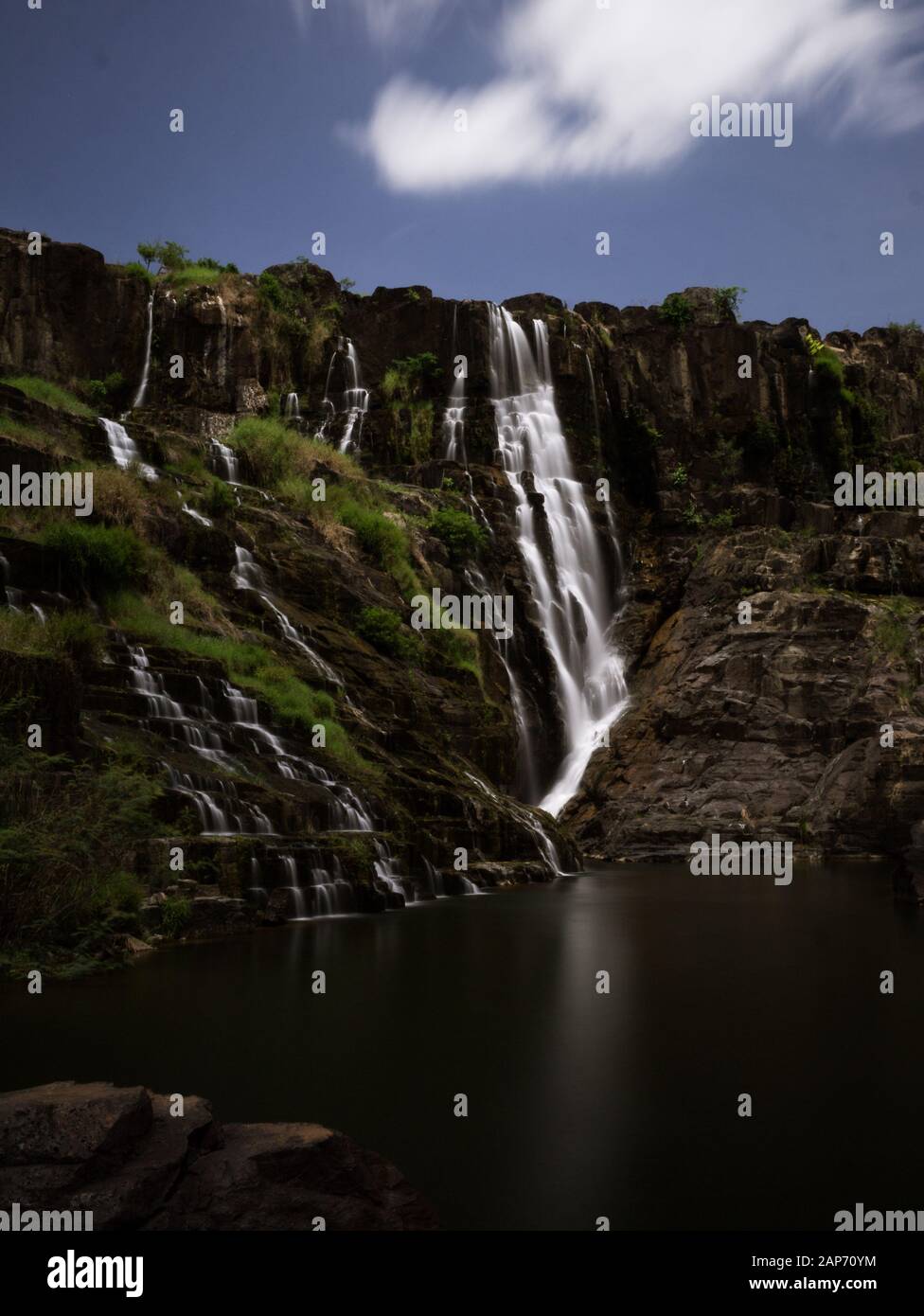 Long-time exposure of Pongour waterfalls nearby Da Lat, Vietnam, on a sunny day with smooth lake surface and flowing water Stock Photo