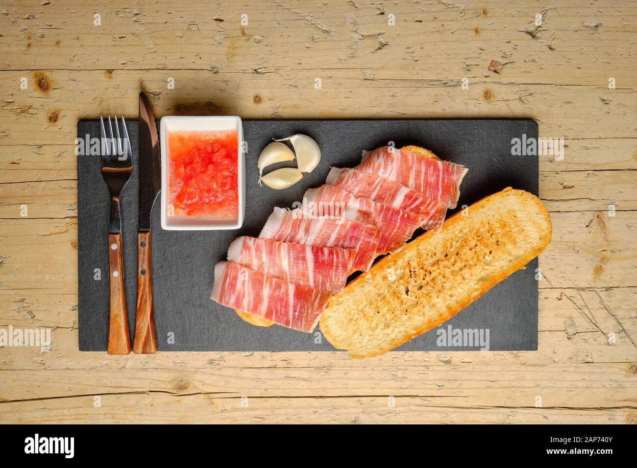 Toast of bread with acorn-fed Iberian ham on stone slate Stock Photo