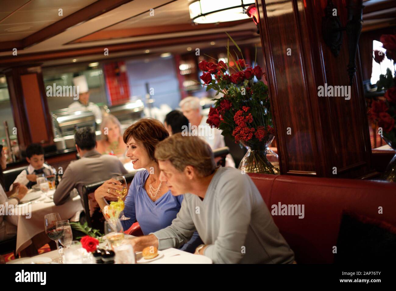 Two mid adults enjoying dinner in a full dining room at a restaurant. Stock Photo