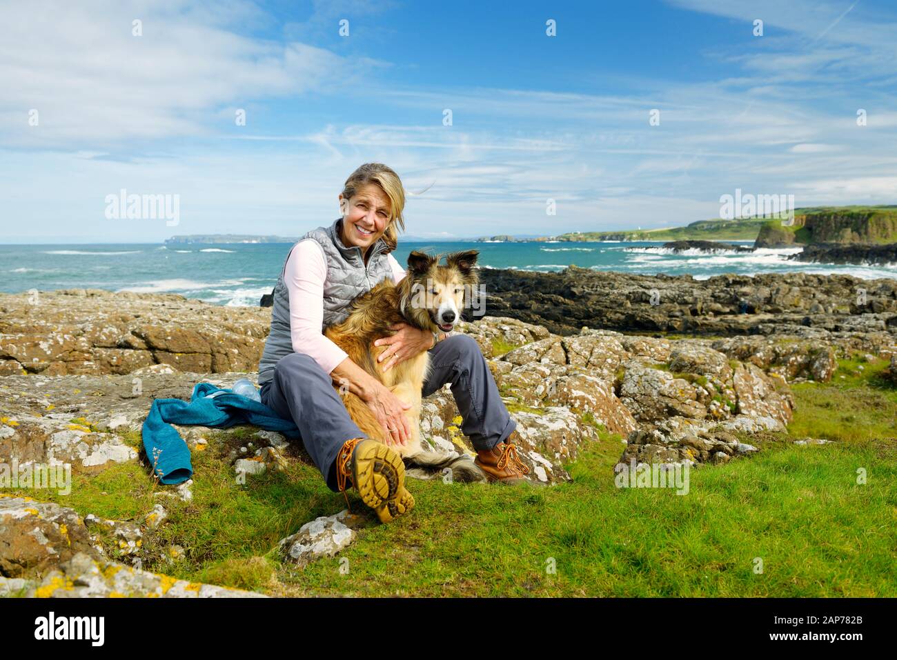 Healthy outdoor middle aged woman summer walking on Ulster Way with border collie dog. Giants Causeway coast at Dunseverick, Co. Antrim, N. Ireland Stock Photo
