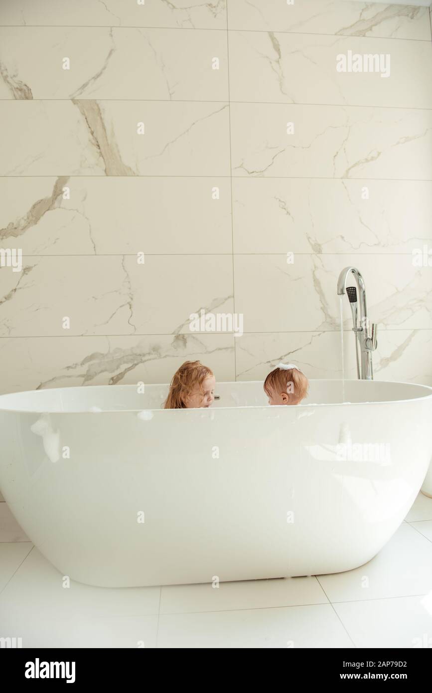 little brother and sister bathing in a foam bath Stock Photo