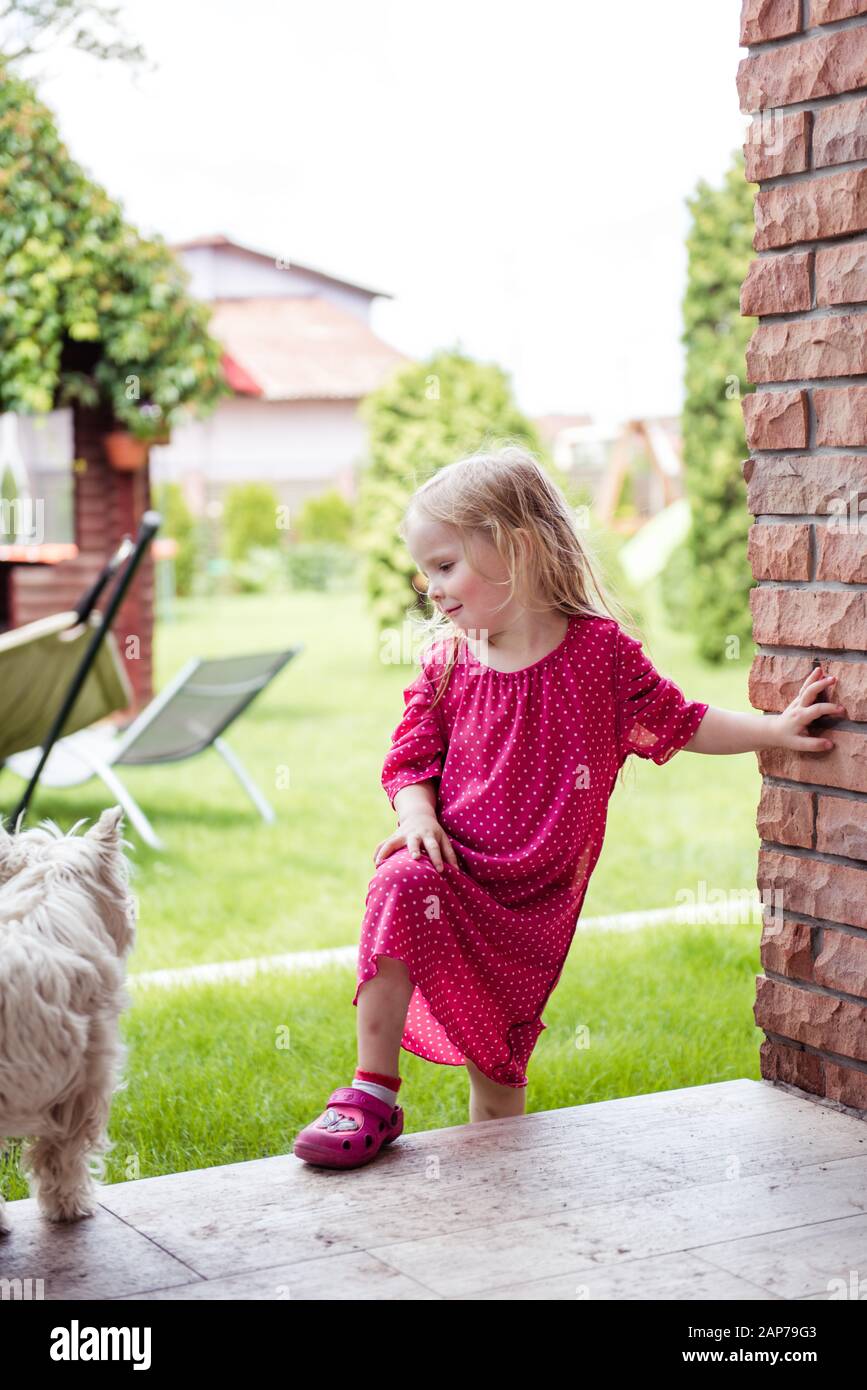 A little girl in the yard playing with a cute white dog Stock Photo - Alamy