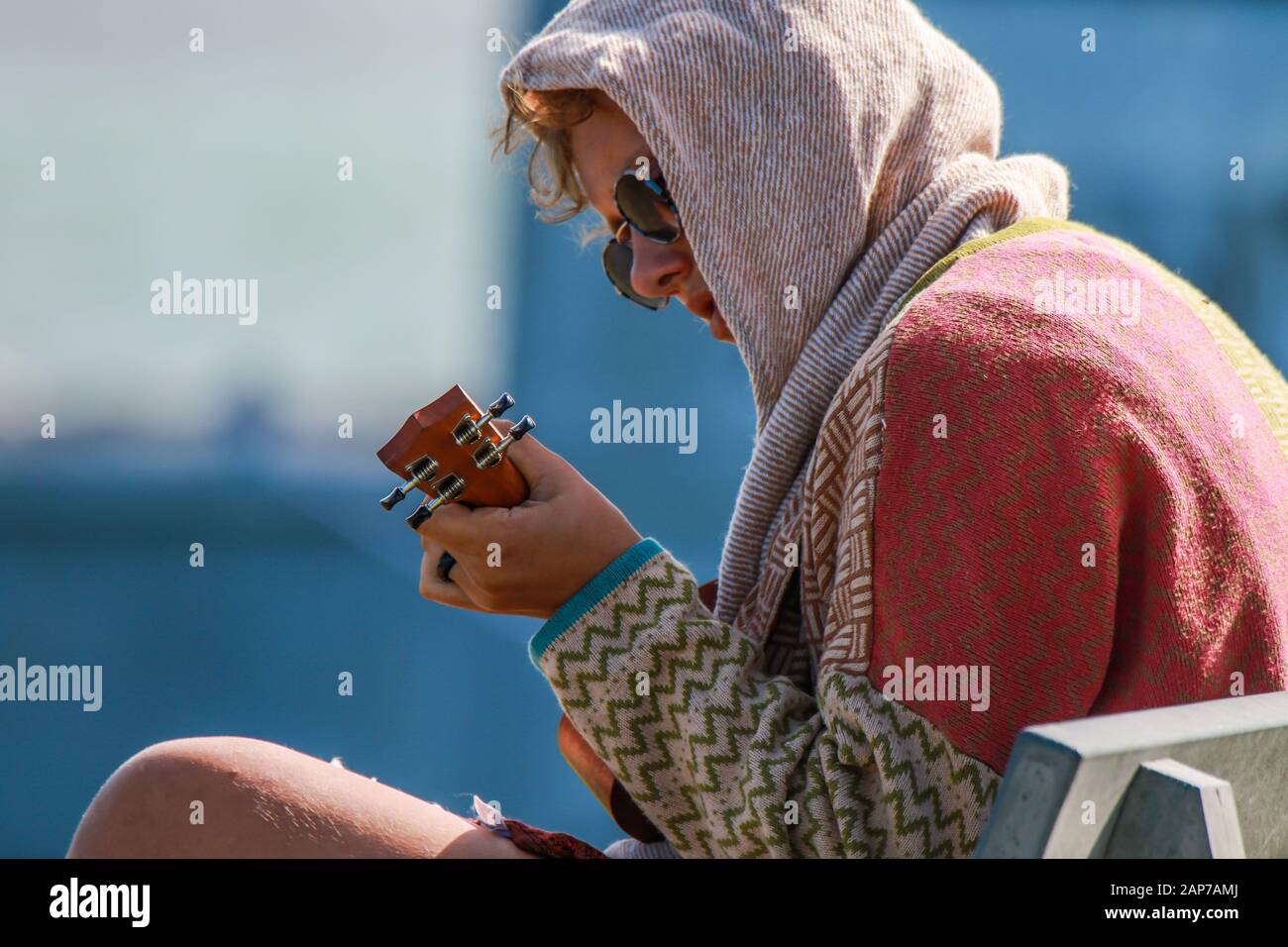 A woman with sunglasses, playing the ukulele Stock Photo
