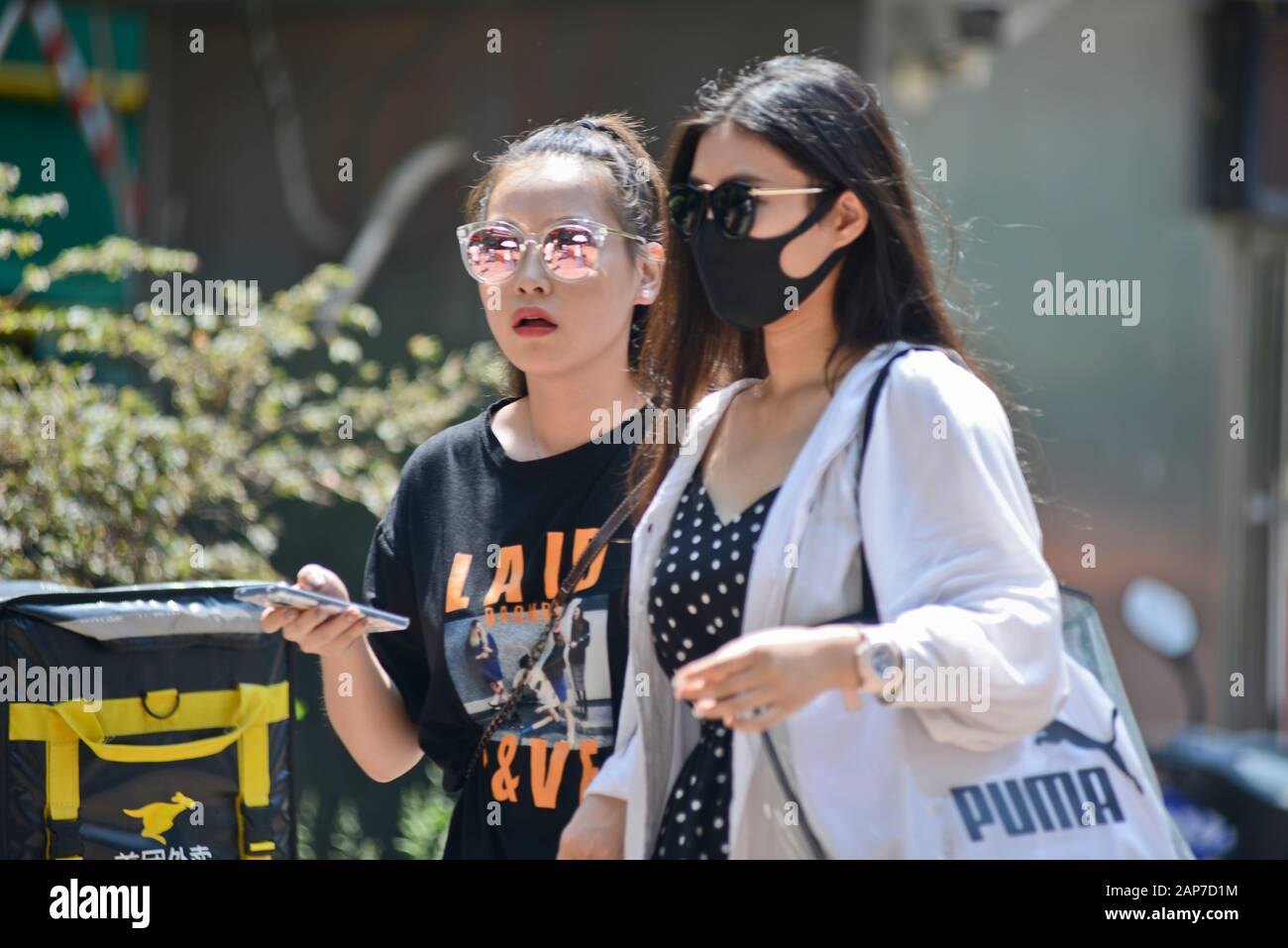 Wuhan (China): spreading of the Covid-19 virus, also known as coronavirus. Chinese girls in Jianghan Road, one wearing a face mask Stock Photo