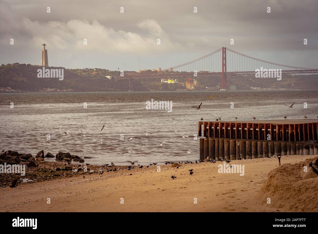 Sandy beach overlooking the Ponte 25 de Abril bridge across the Tagus river, Lisbon, Portugal Stock Photo