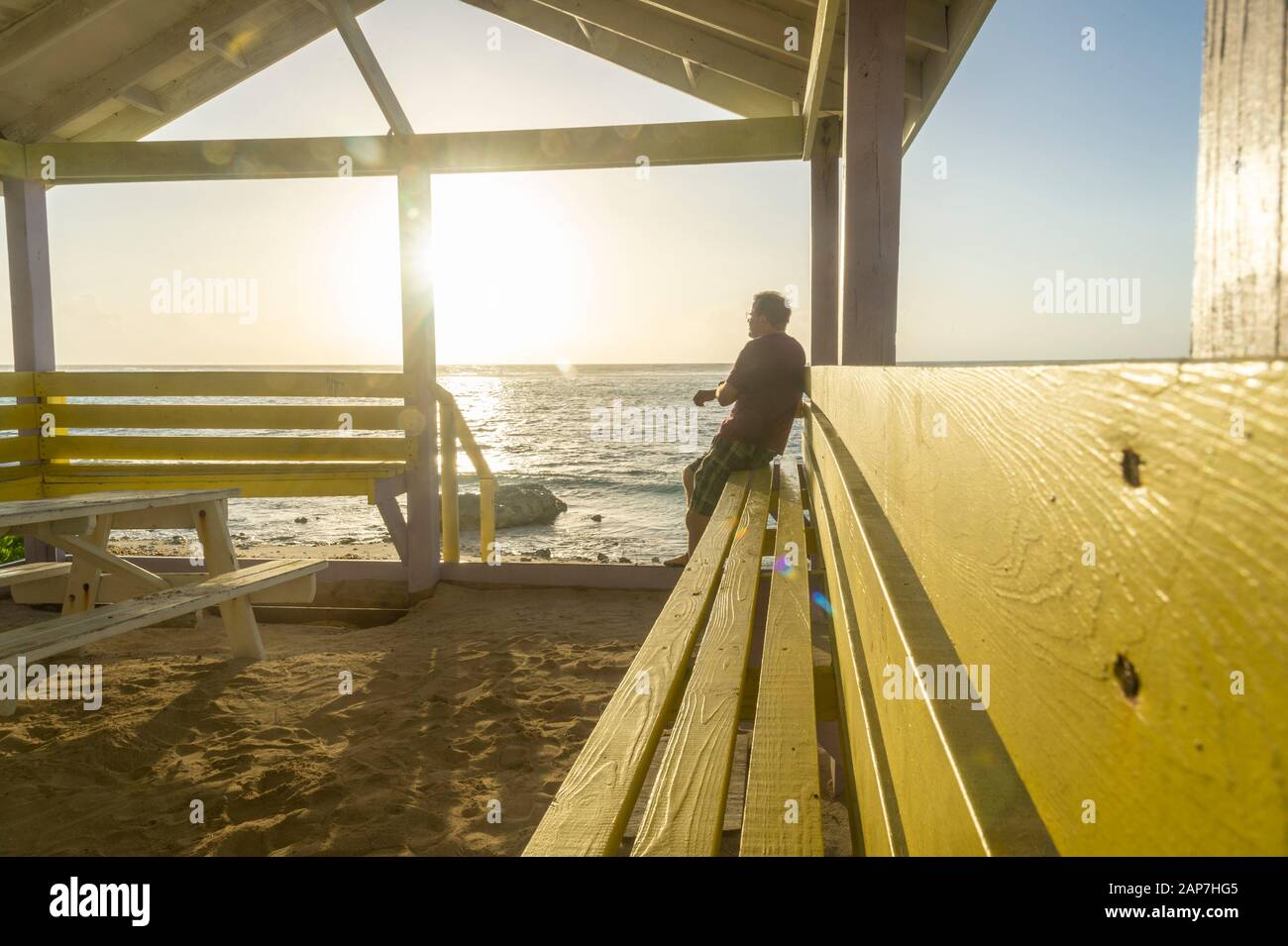 Man in solitude looking at sunrise ocean contemplatively Stock Photo