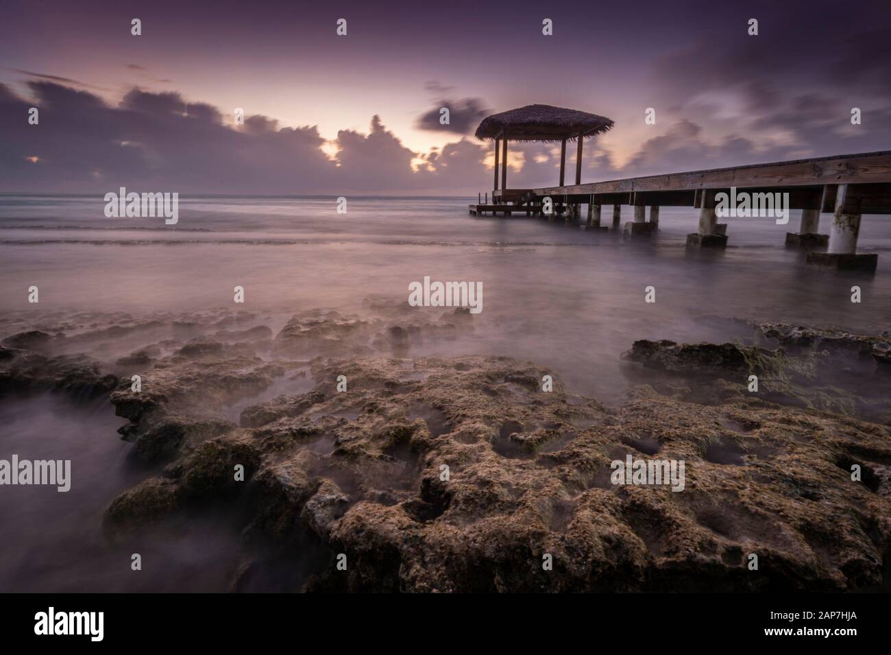Gazebo on pier with misty waves crashing on rocky shore, Grand Cayman Island Stock Photo