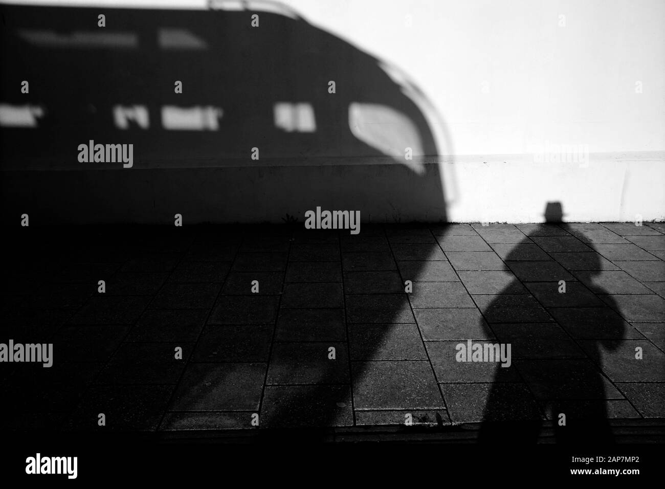 Shadow of a double decker bus and photographer on a stark white wall in ...