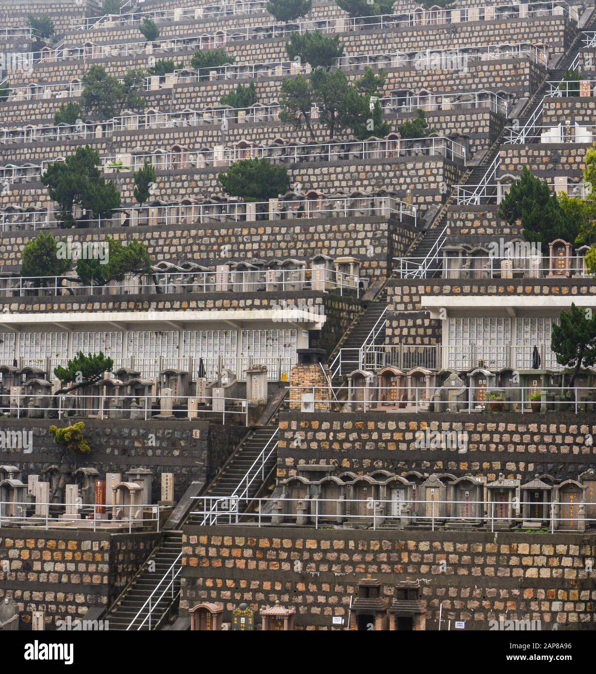 Hong Kong - March 9, 2019 - Stairway on a hillside of numerous tombstones in a crowded Hong Kong cemetery Stock Photo