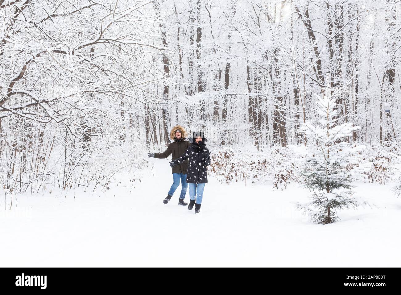Happy couple walking through a snowy forest in winter Stock Photo - Alamy