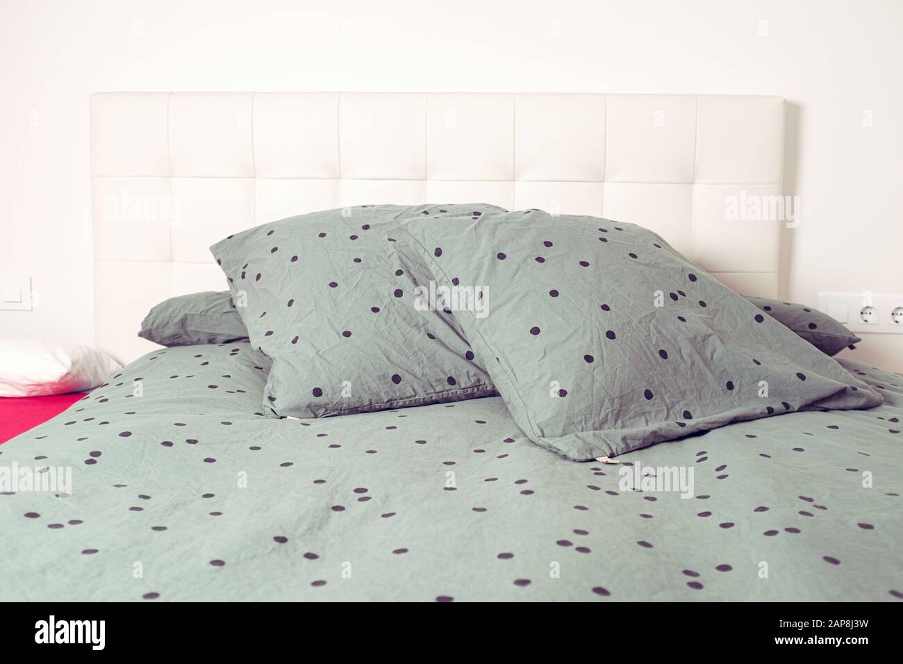 Green pillow and sheets with black spots on an interior bedroom home scene Stock Photo