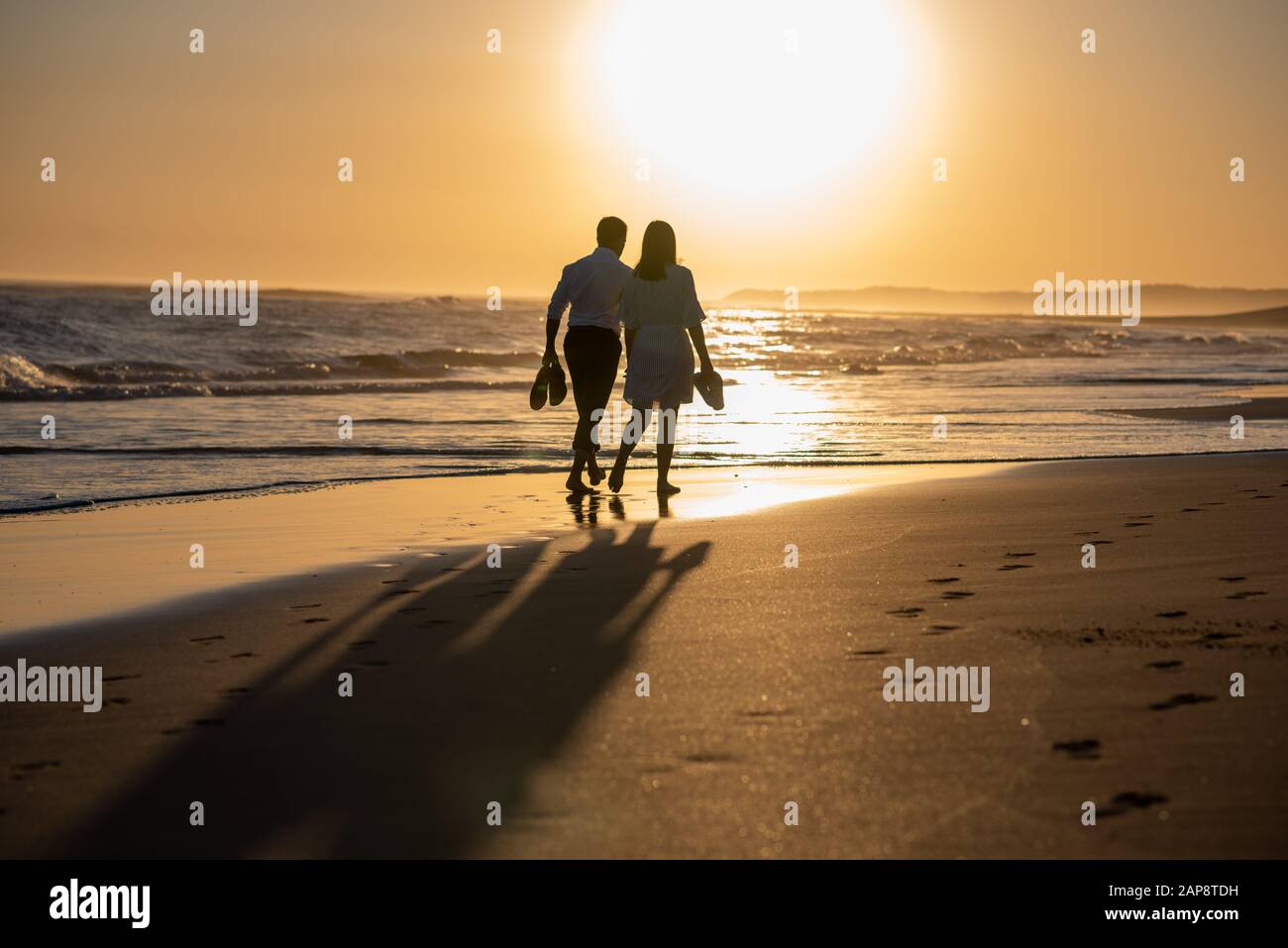 Silhouette of couple walking on beach during sunset Stock Photo - Alamy