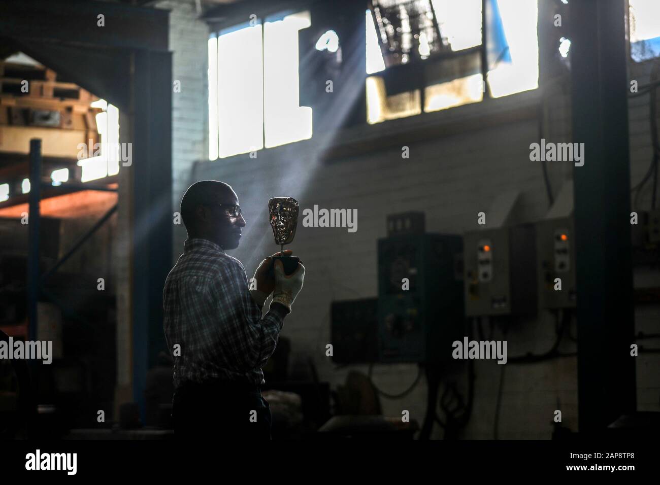 Moulder Rupert Francis looks at a finished mask during the casting of the British Academy of Film and Television Awards (BAFTA) masks at a foundry in West Drayton, west London, ahead of the ceremony on February 2. Stock Photo