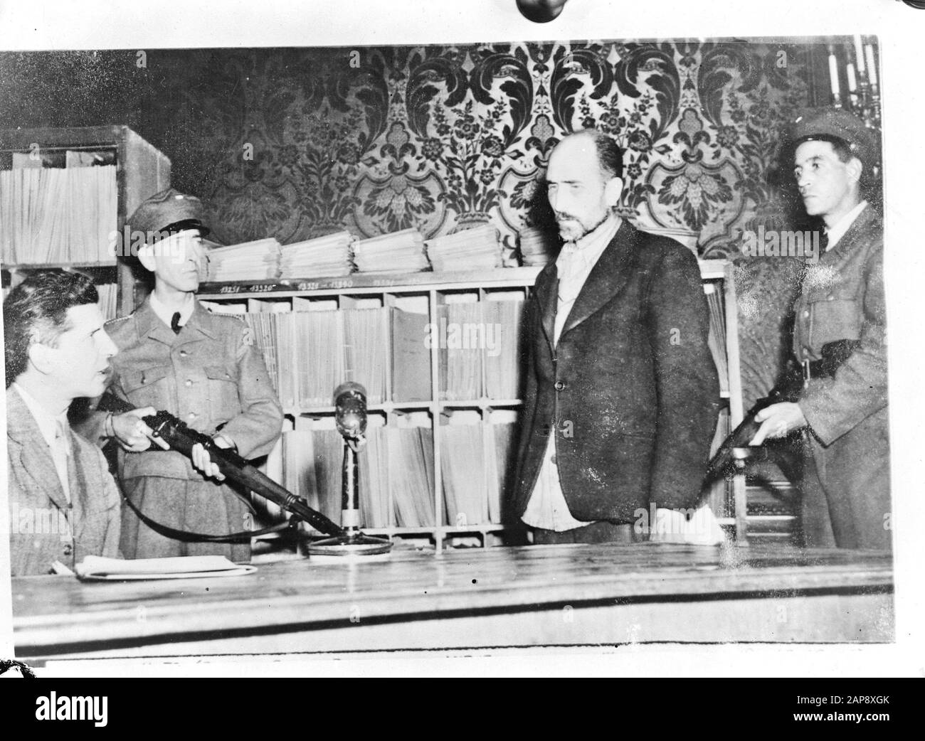 The executioner of Auschwitz [Maximilian Grabner (standing) leader of the Political Department of Concentration Camp Auschwitz is questioned by Dr Heinrich Dumayer, head of the Viennese police and former interned of Auschwitz] Annotation: Repronegative. The interrogation took place in early September 1945. The repro is dated 28-12-1945. This photograph was published in two newspapers on 3 and 5 January 1946. Grabner then has a wrong first name in both captions (Wilhelm) and is mistakenly called commander of Auschwitz. Grabner was sentenced to death in December 1947 in Poland and hanged in Janu Stock Photo
