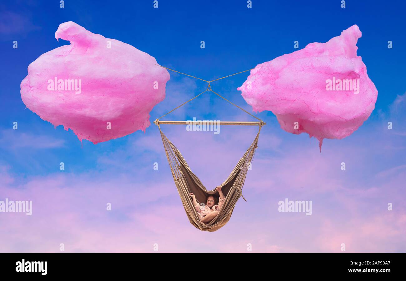 Cotton candy cloud hammock. Young girl relaxes in a hammock between two clouds made of cotton candy. Conceptual, illustrative image composition. Stock Photo