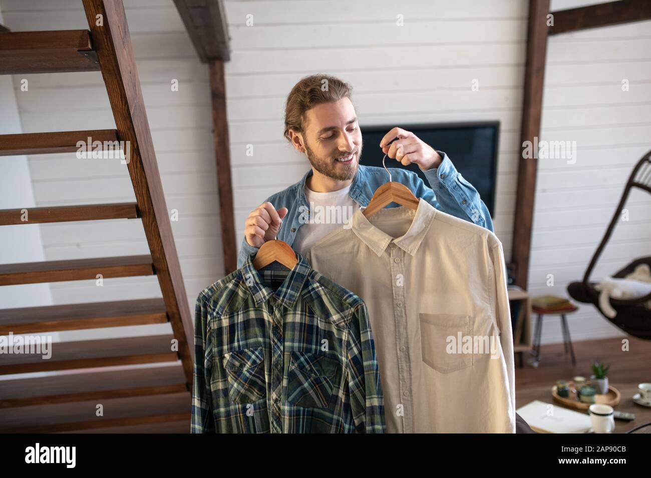 Man choosing between plaid and white shirt Stock Photo