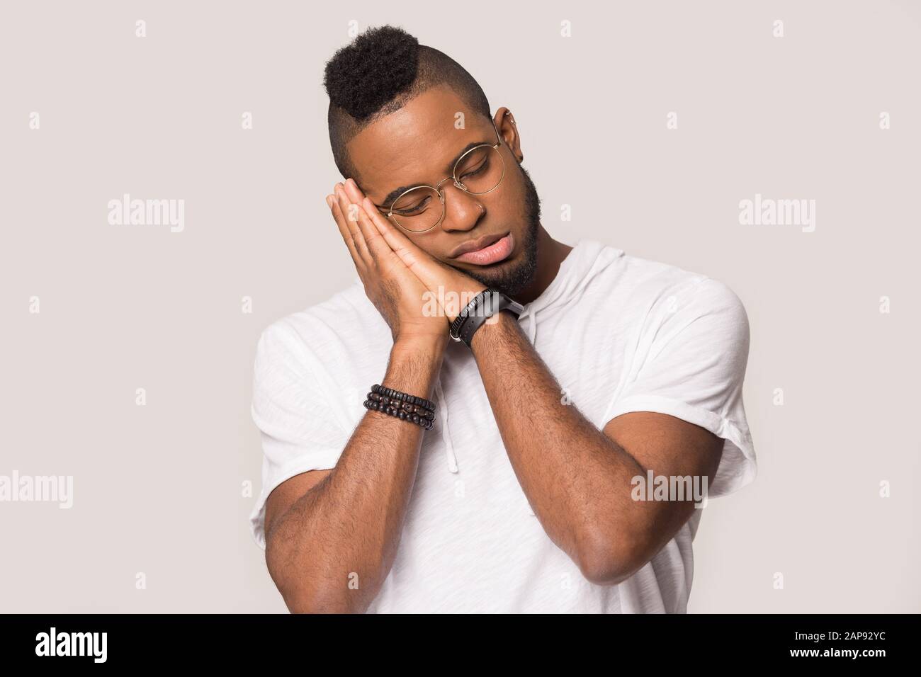 Tired black man standing in studio sleeping head on hands Stock Photo