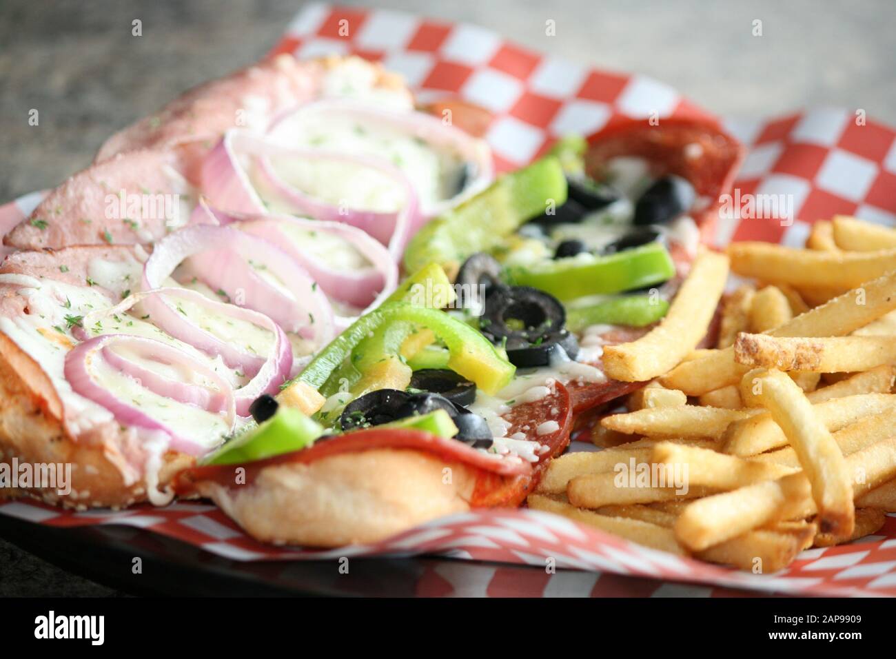 toasted open faced deli sandwich with green peppers, black olives, melted mozzarella cheese and french fries on the side pub or deli restaurant food Stock Photo